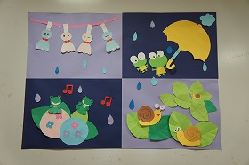 雨が降る中、カエルやカタツムリが楽しそうに歌っている壁面装飾です。