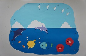 真っ青な空を背景に、イルカやマンボウ、タコたちが楽しそうに飛び跳ねたり泳いだりしている壁面装飾です。