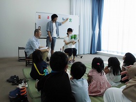 絵本を読む学生ボランティアたちと見る子供たち