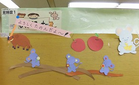 「よろしくたのんだよ」と書かれた旗を持ついのししと4ひきのねずみの切り紙装飾