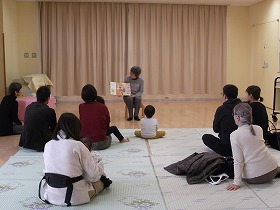 絵本の読み聞かせをする演者ときいている親子