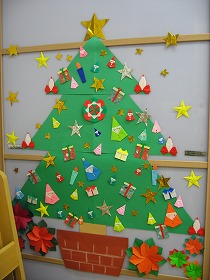 大きなクリスマスツリーに、色画用紙や折り紙でできたカラフルなサンタさんやオーナメント、星が飾られている。
