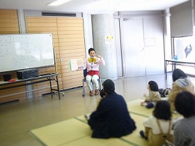 1、演者が絵本を読んでいる写真。